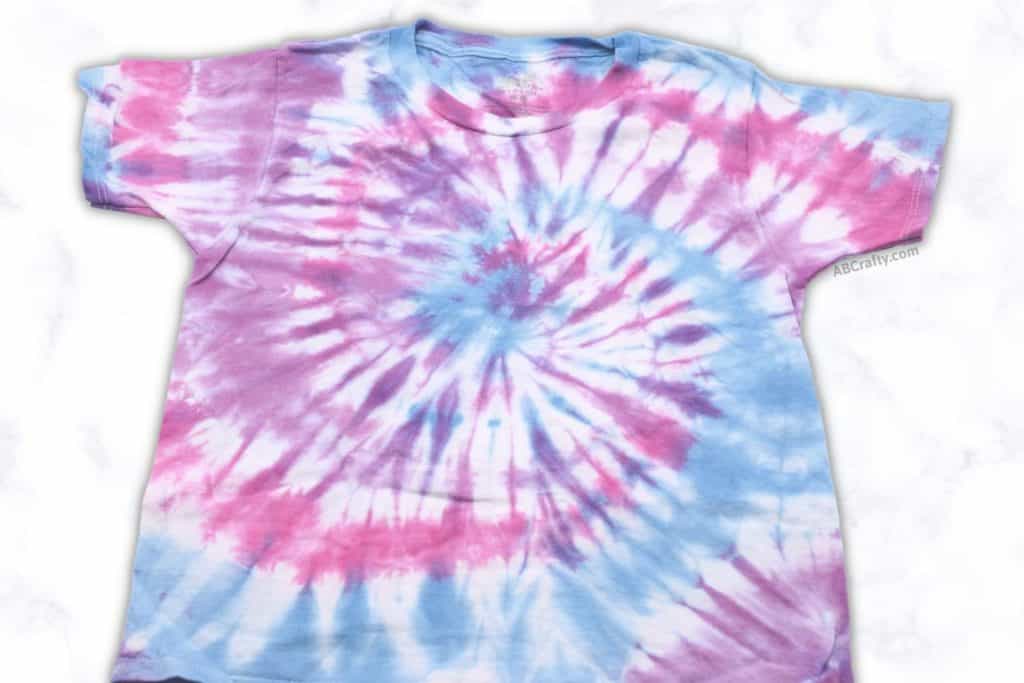 finished pastel tie dye shirt with a pink, blue, and purple spiral tie dye design