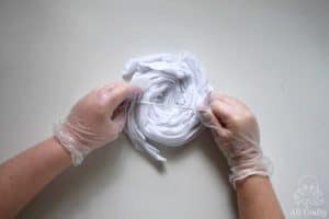 putting a rubber band around a twisted up white cotton shirt