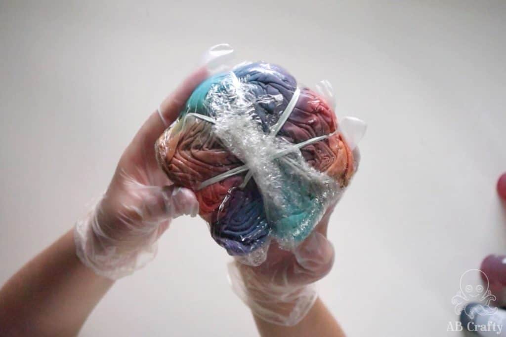 fully dyed shirt with pink, orange, blue, and purple dye wrapped in plastic wrap