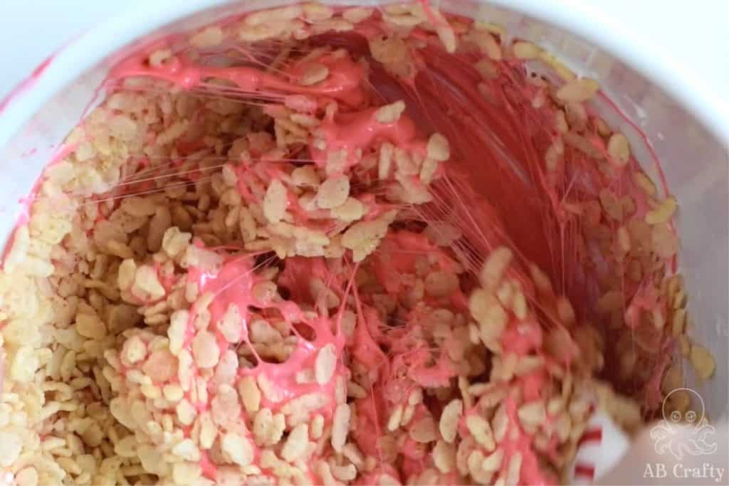 mixing rice krispies into the red marshmallow mixture
