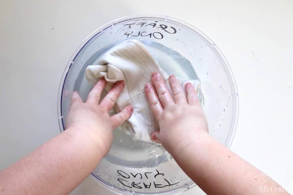 putting a white cotton hat into a bowl of water