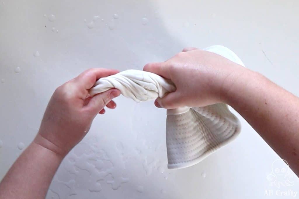 twisting the top of a white cotton bucket hat