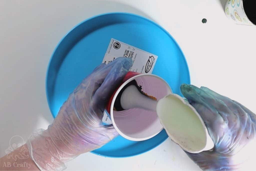 pouring conditioner into the side of a cup to create layers of conditioner and dye