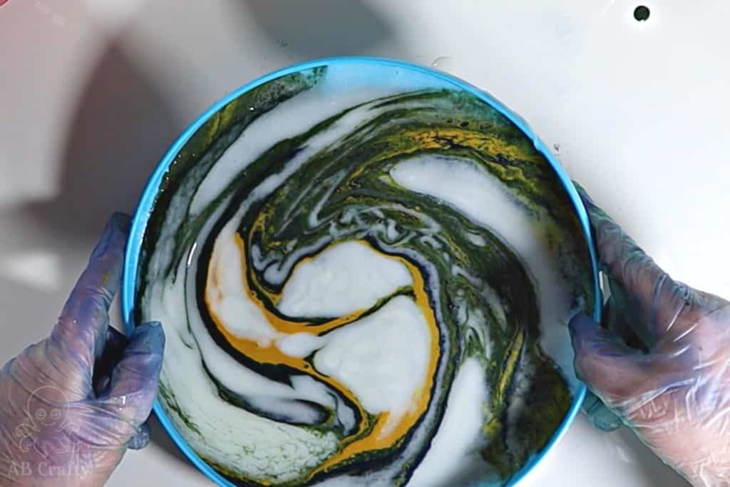tilting a plastic frisbee with conditioner and dye to swirl the colors