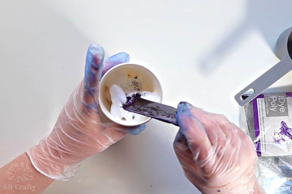 pouring purple idye poly from the packet into a paper cup with shaving cream in it