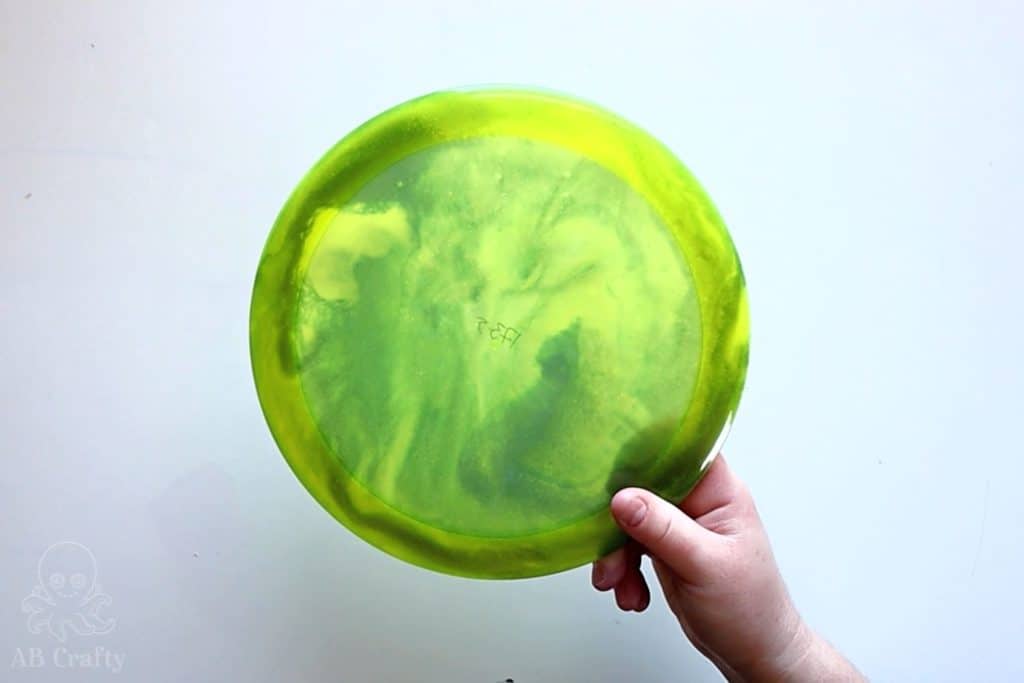 holding the finished yellow dyed disc golf disc