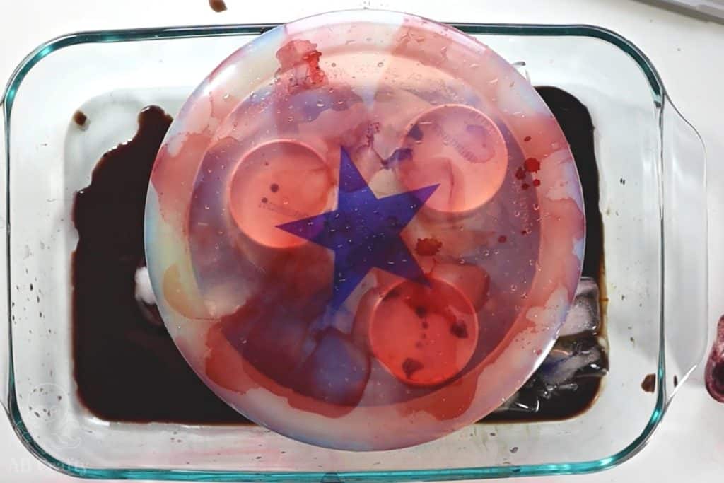 dyed disc golf with a blue start in the middle and red and blue dye across the disc over a glass dish with ice and dye