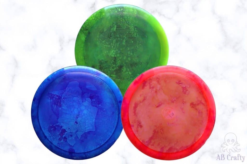 3 dyed disc golf discs in purple, green, and red