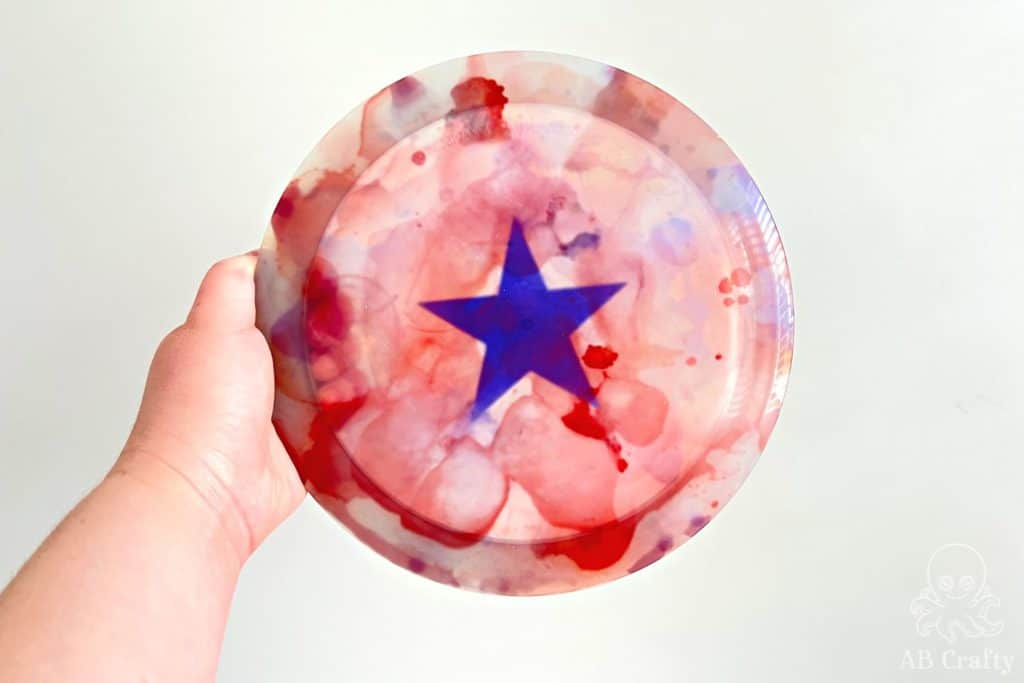 holding a clear disc golf disc with a blue star and red and blue water color design