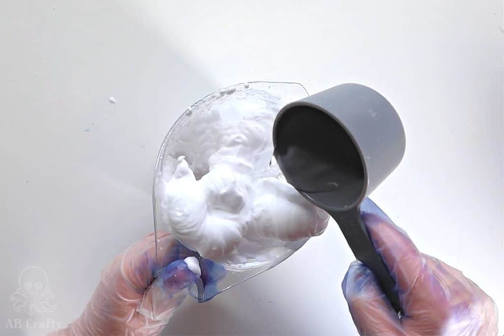 pouring water from a measuring cup into a larger measuring cup with shaving cream in it