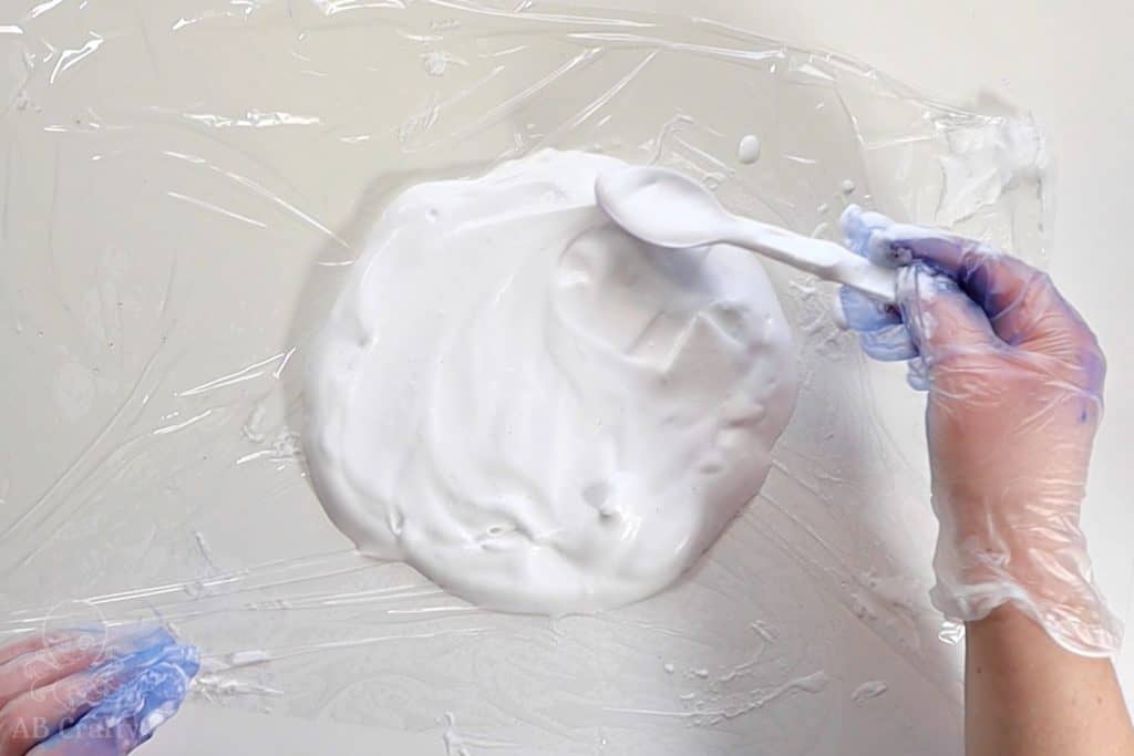 using a plastic spoon to smear shaving cream into a circle on plastic wrap