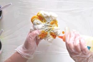 pouring yellow dye from a squeeze bottle onto the white tied up shirt