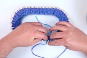 placing the first loop over the first knitting loom peg