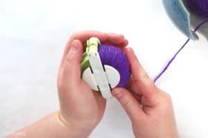 half of the green clover pom pom maker filled with purple yarn