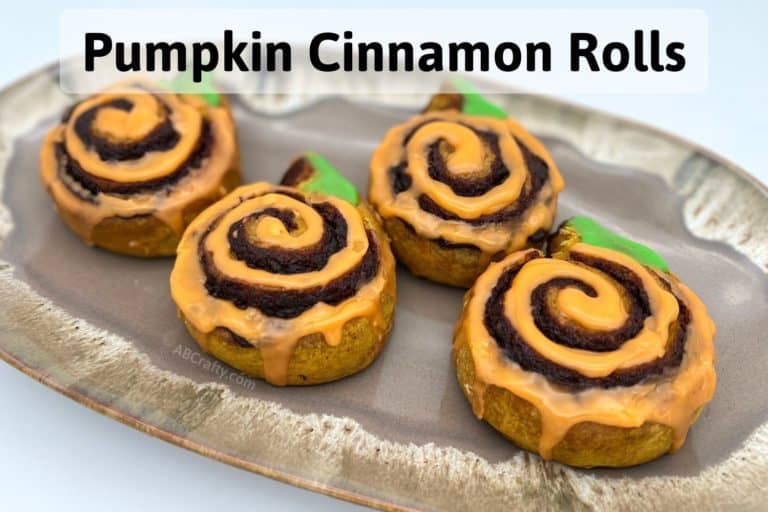finished wildgrain cinnamon rolls with orange icing in a spiral and green icing for the stem and the title "pumpkin cinnamon rolls"