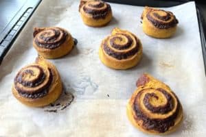 golden brown cinnamon rolls on a baking sheet out of the oven