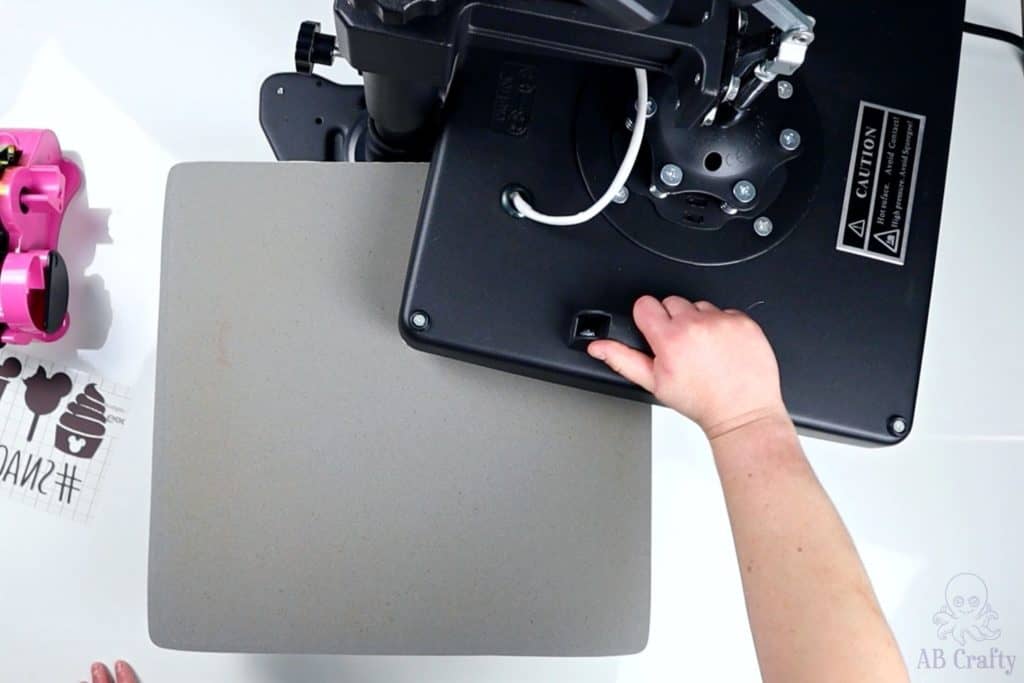 pushing the top of a swing heat press away, revealing the bottom plate