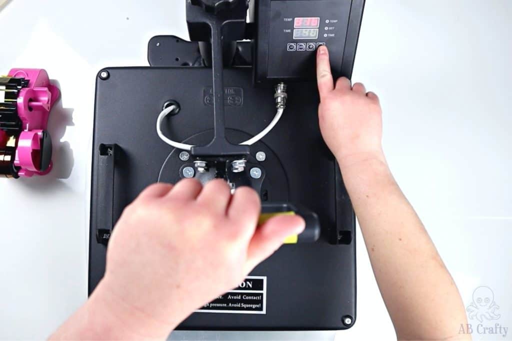 pulling down on the lever of the heat press and pressing the button for the timer