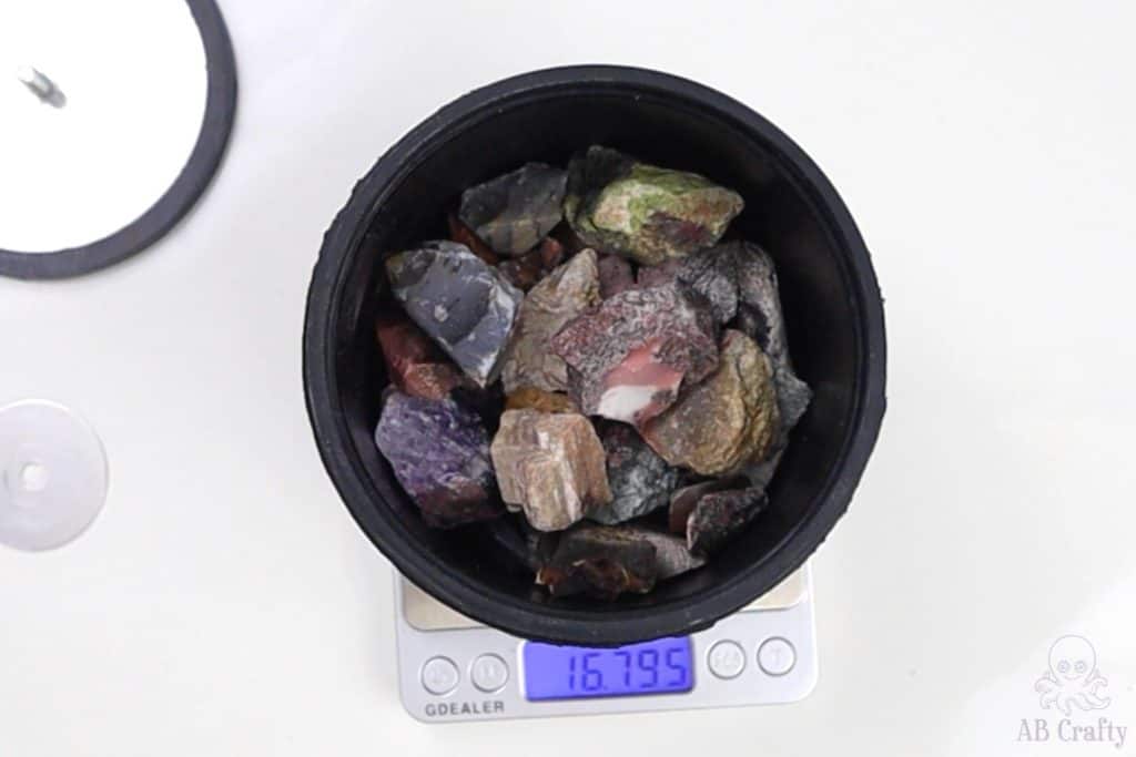 various raw stones in a barrel getting weighed on a scale