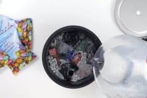 pouring water into the komestone barrel with raw stones and ceramic pieces