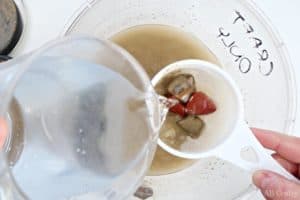 using a small sifter to rinse stones over a bucket