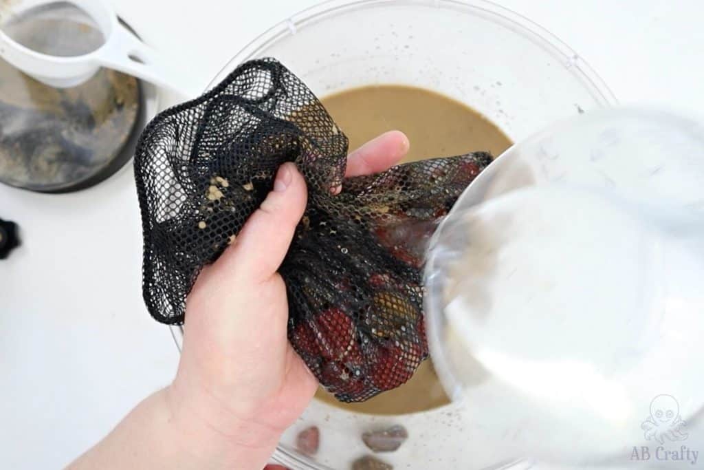 rinsing the stones in the mesh bag over a bin