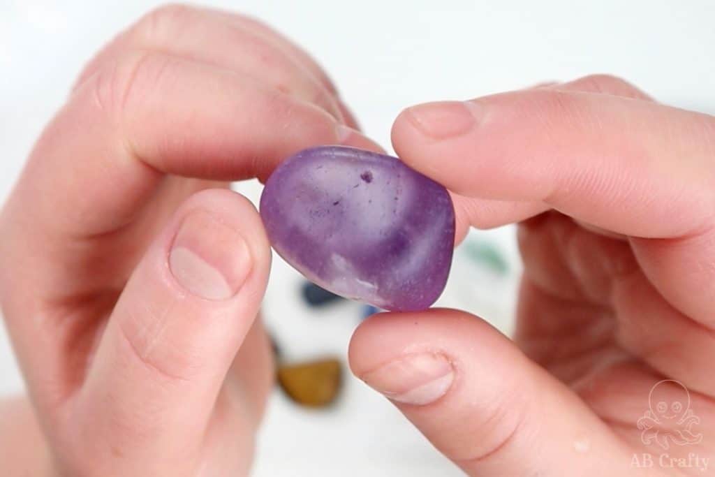 holding an amethyst that's been through the first step of polishing, showing the holes in it