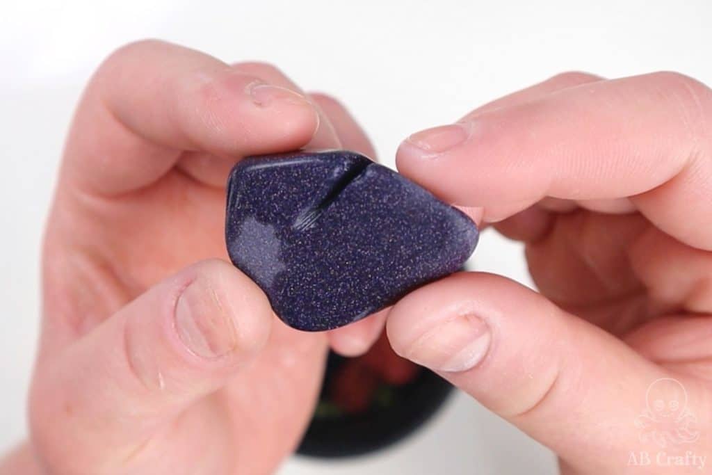 holding blue goldstone after the first stage of tumbling, showing the crack in the middle of it