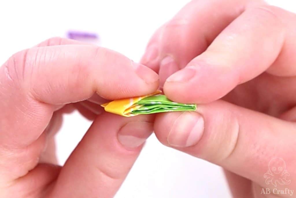 inserting a folded green candy wrapper into a yellow folded one