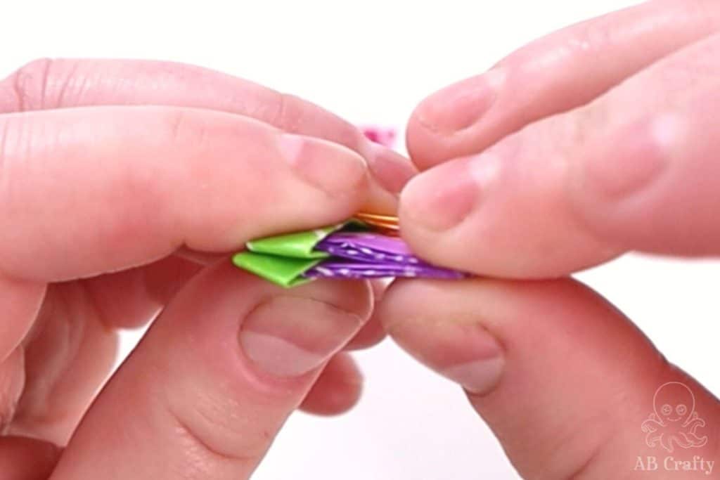 inserting a folded purple candy wrapper into a green folded one