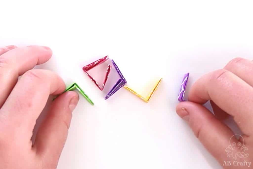 multiple candy wrappers in different colors folded, ready to make a chain