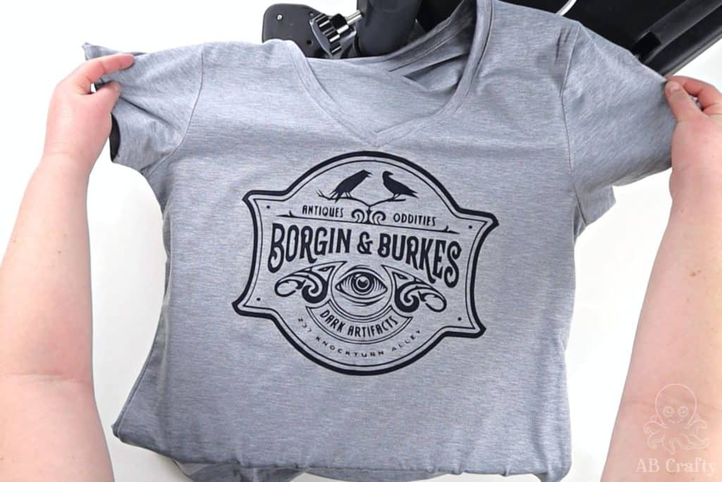 holding the finished sublimation shirt on the heat press with the borgin and burkes logo