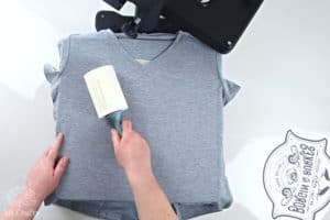 using a lint roller on a cricut infusible ink shirt on top of a heat press