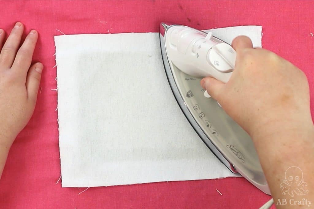 ironing the back of the cloth on a pink ironing mat