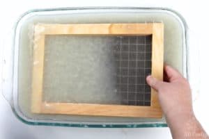 dipping the formed paper making kit into a dish with paper pulp