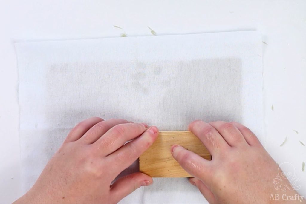 using a wood block to press the water into the cloth