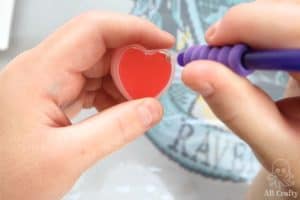 dipping the tool into red wax in the shape of a heart