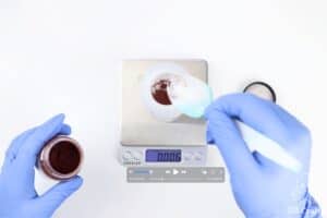 plastic spoon pouring powdered dye into a bottle on a food scale