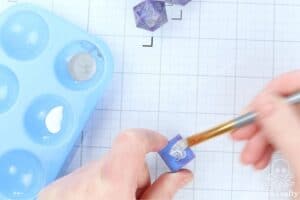 using a brush to paint white acrylic paint onto the die face