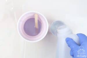 pouring epoxy resin into a measuring cup with a larger cup next to it that already contains resin