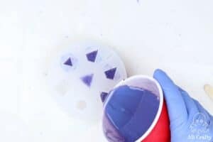 pouring purple epoxy resin into a lets resin dice mold mold