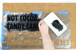 painting black paint across the doormat stencil