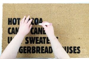 using the cricut weeding tool to remove vinyl from the custom doormat