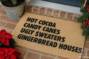 christmas doormat with the words "hot cocoa, candy canes, ugly sweaters, gingerbread houses" in front of a door outside