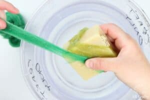 pulling green wool roving across a bar of soap